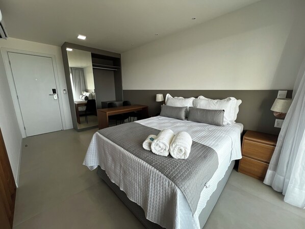 A hotel room with a large bed, a desk, a chair, a mirror, and a nightstand. - RN STUDIO APTO 1002 (Maceió)