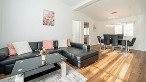 A modern living room with a sectional sofa, a coffee table, and a dining area with chairs and a table.