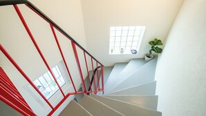 A staircase with red railings and a view of the outside through a window.