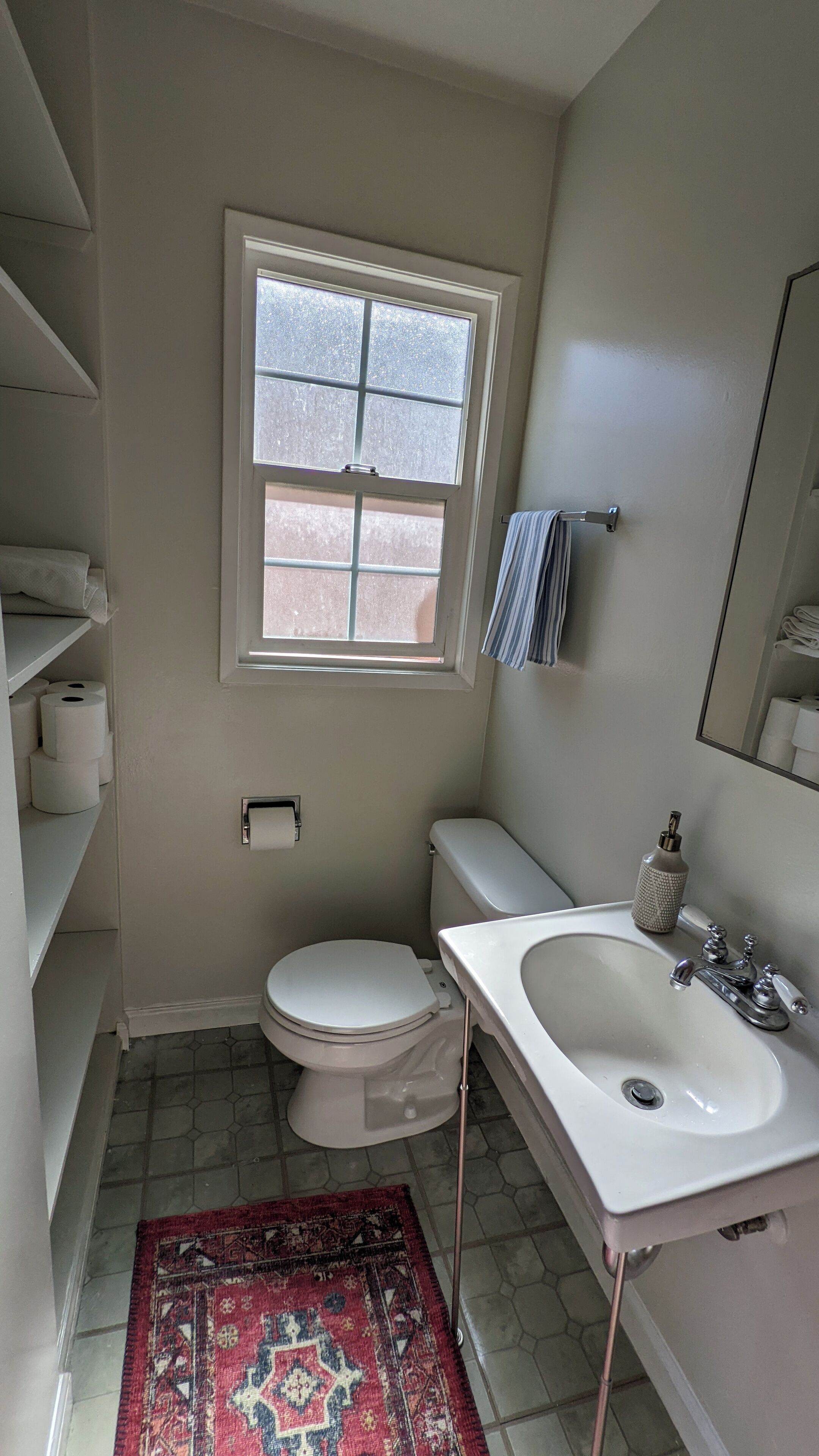 A small bathroom with a toilet, sink, and window.