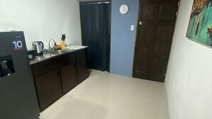 A small kitchen with a refrigerator, sink, and cabinets.