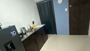 A compact kitchen with a refrigerator, sink, and cabinets.