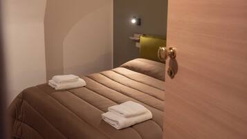 Une chambre à coucher avec un lit, une table de chevet et une lampe fixée au mur.