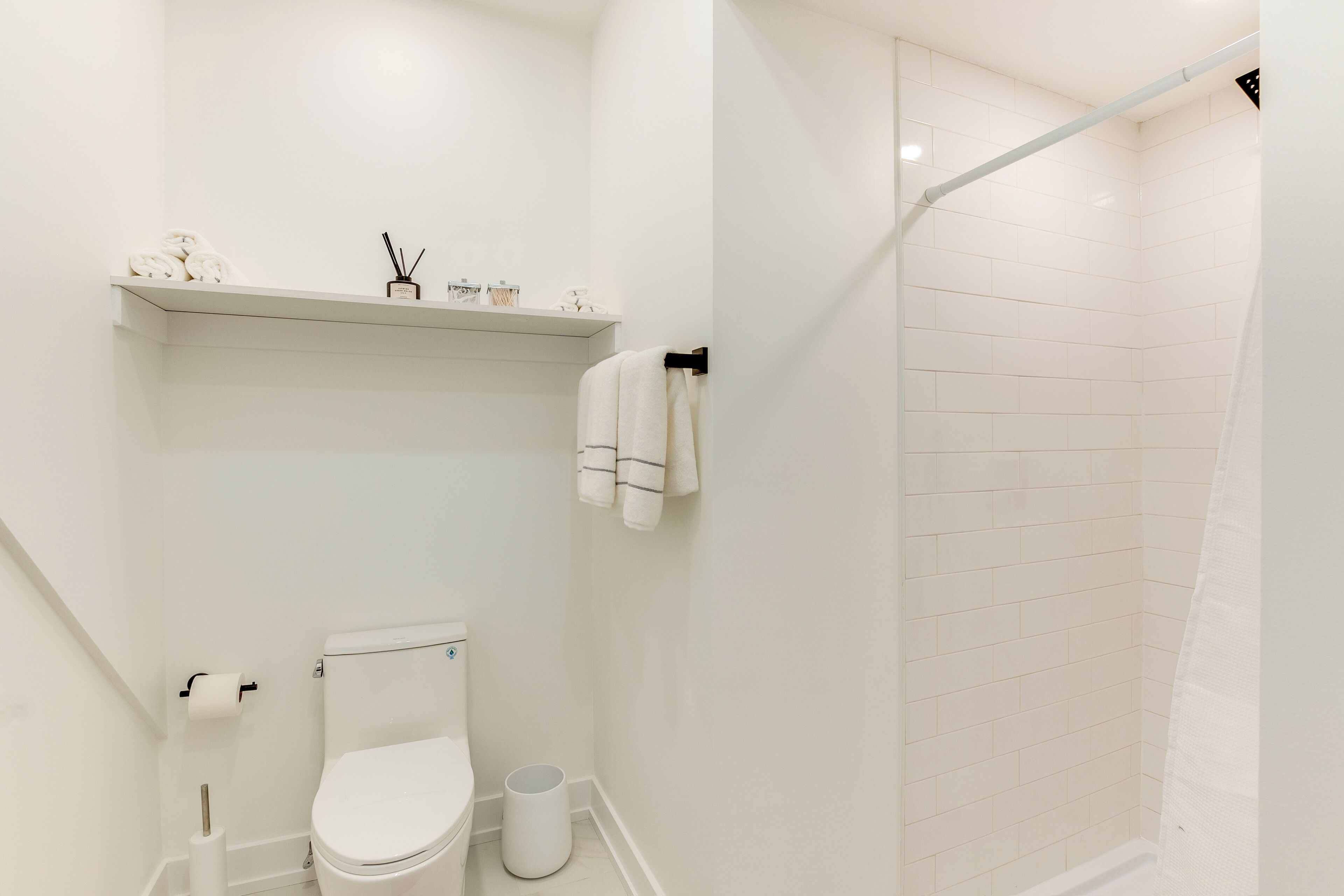 Ein modernes Badezimmer mit Toilette, Dusche und Ablage für Pflegeprodukte.