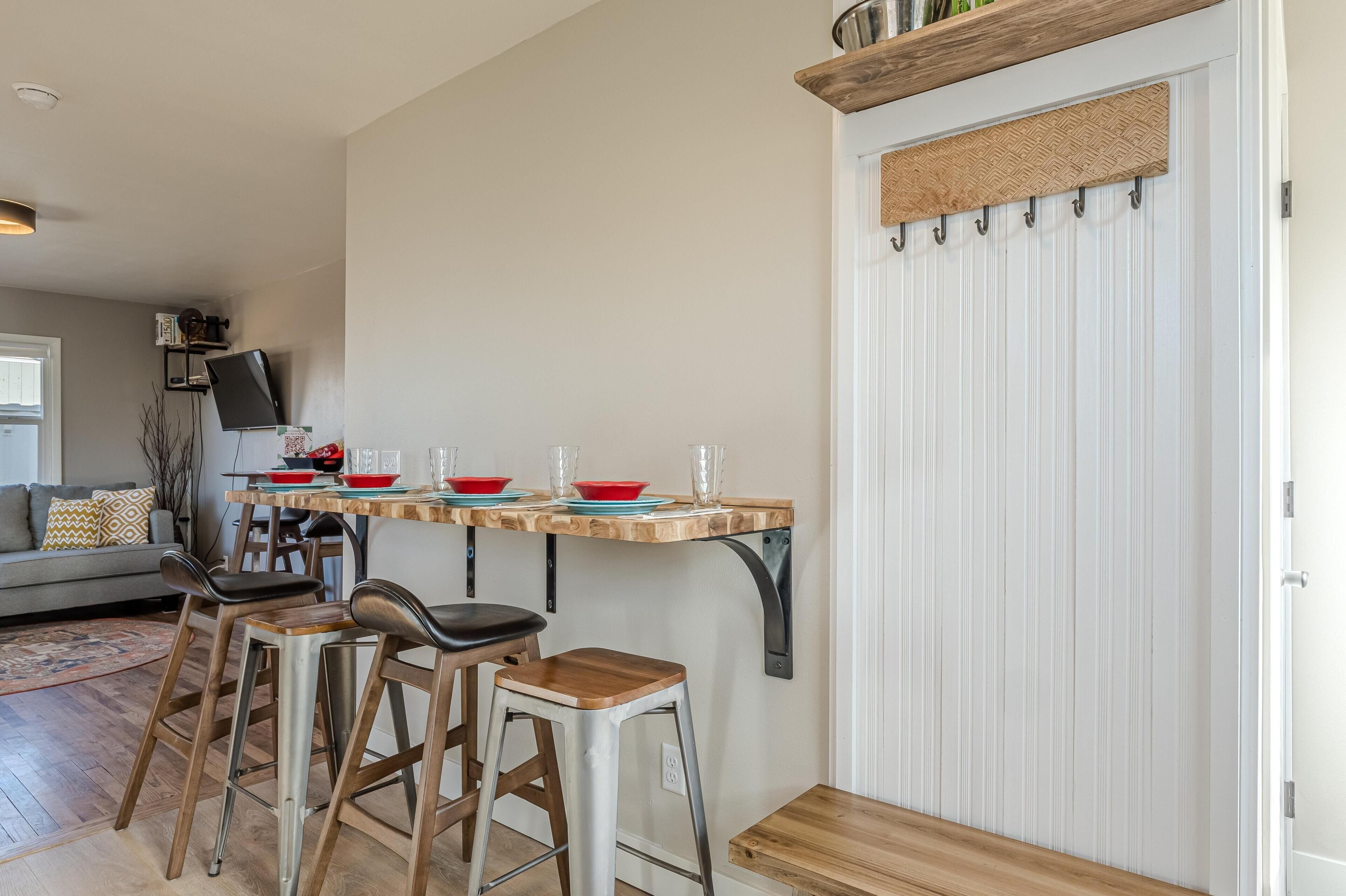 Eine Küche mit einer Holzausziehtheke, Hockern und einer weißen Tür mit Fußmatte.
