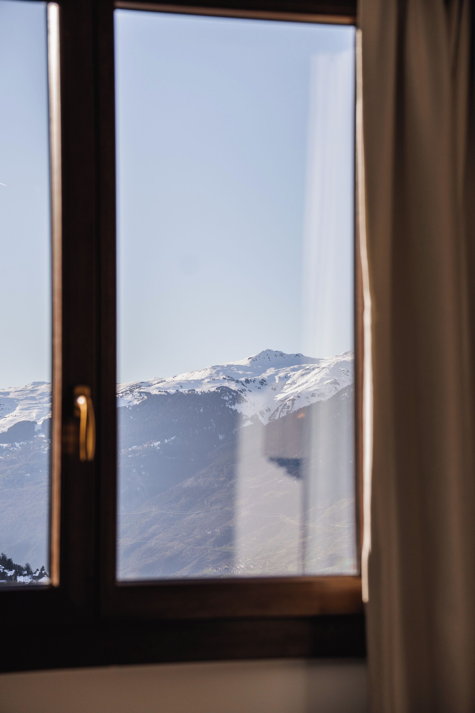 Una ventana con vista a montañas nevadas.