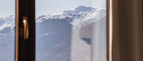 Una ventana con vista a montañas nevadas.