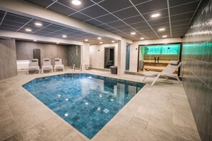 A swimming pool with lounge chairs, a changing room, and a sauna area. - Hôtel Emeraude (Landry)