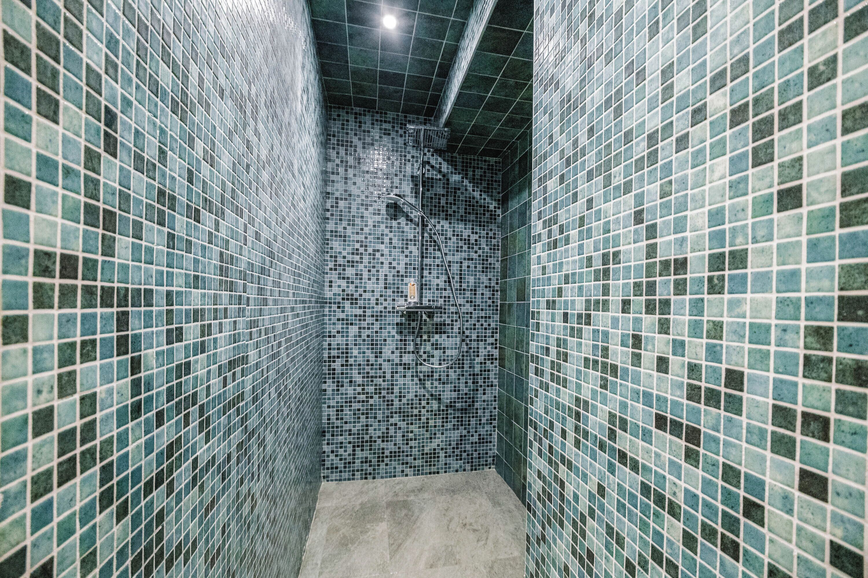 A narrow tiled bathroom with a shower area.