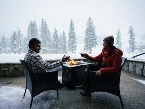 Enjoy a serene meal or conversation in this peaceful outdoor seating area, surrounded by snow-covered trees.
