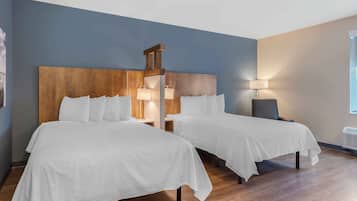A hotel room with two beds, wooden headboards, and bedside lamps.