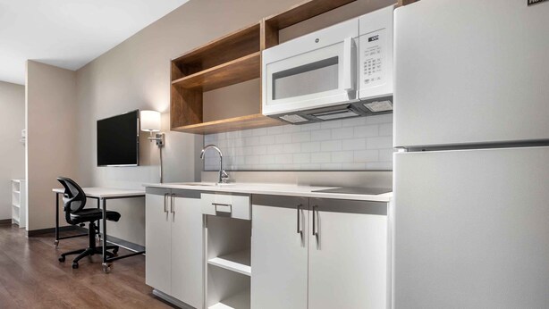 Une cuisine moderne avec des armoires blanches, un four à micro-ondes, un évier et une chaise.