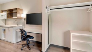 A modern kitchen with a microwave, sink, and cabinet, a black office chair, and a TV mounted on the wall. - Extended Stay America Premier Suites - Charlottesville (Charlottesville)