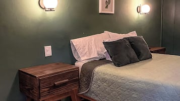 A bedroom with a bed, bedside tables, and wall-mounted lights.