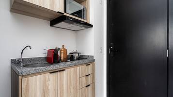 Una cocina con puerta negra, armarios de madera, campana extractora de acero inoxidable y encimera de granito.