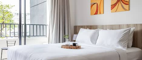 Une chambre d’hôtel avec un lit, une fenêtre avec des rideaux, une vue sur l’extérieur et deux œuvres d’art murales.