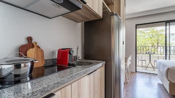 A modern kitchen with granite countertops, a stainless steel refrigerator, and a red coffee machine.