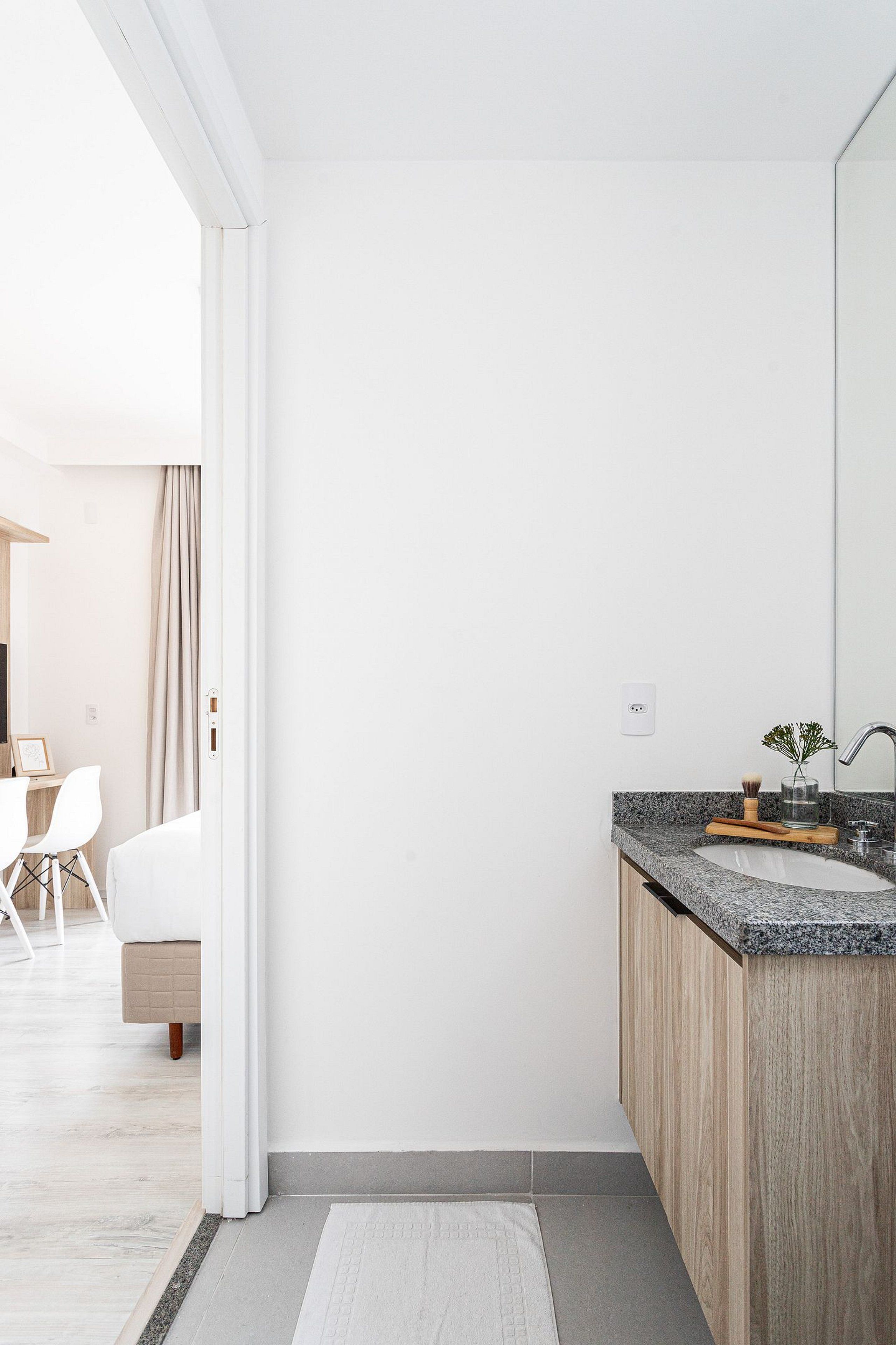Un baño moderno con encimera de granito, mueble de madera y un espejo grande.