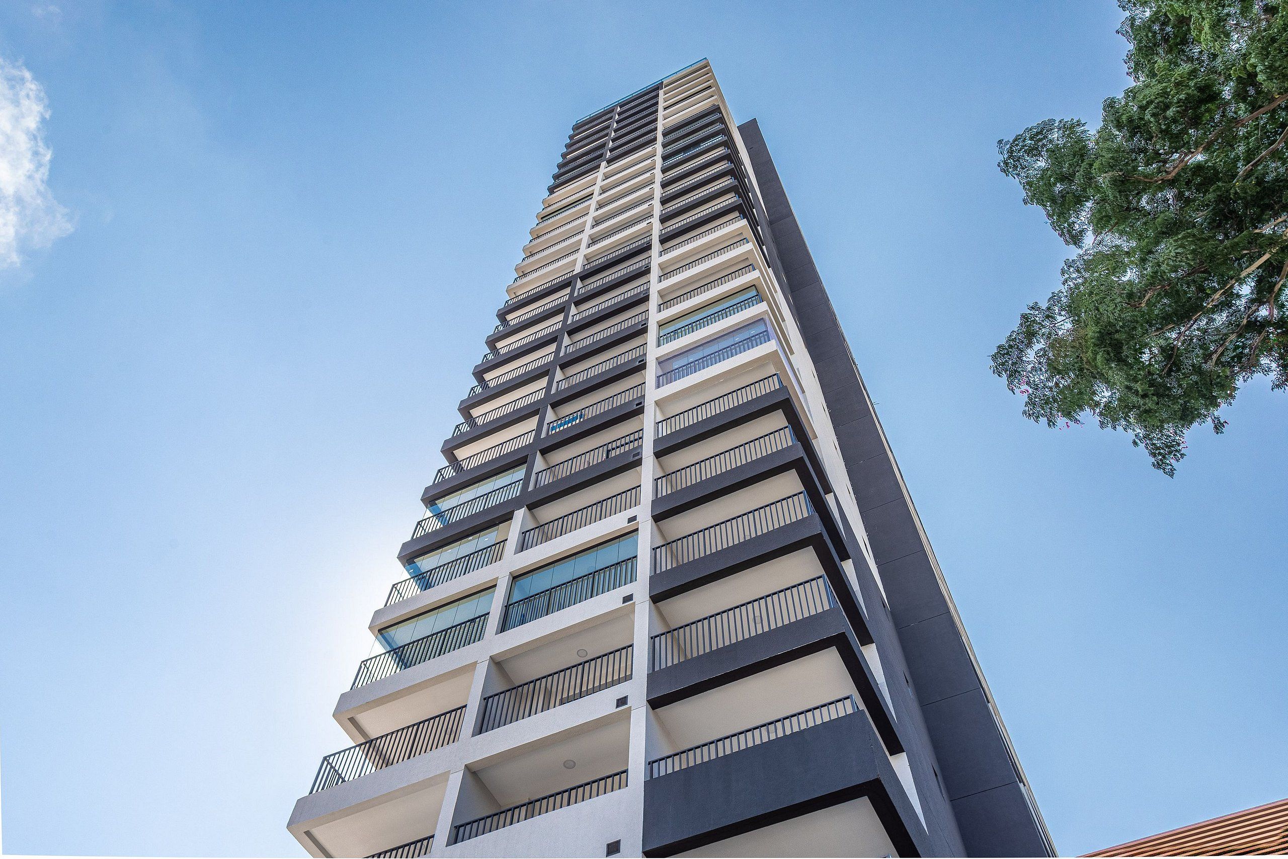 Um edifício alto com várias varandas e céu claro.