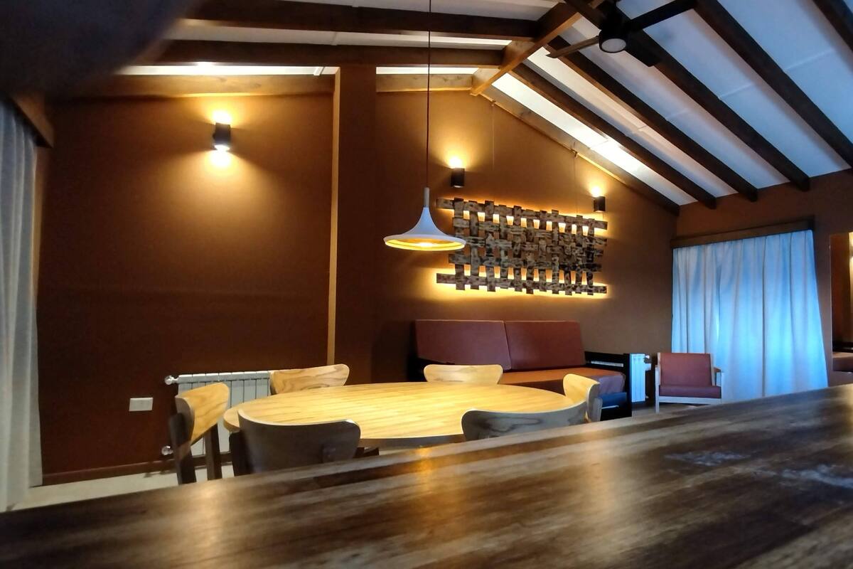 Un espace repas moderne avec une table ronde, des chaises en bois et un luminaire mural original.