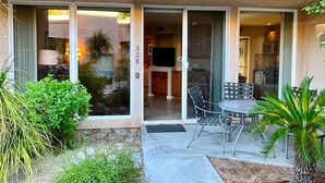 Un immeuble résidentiel doté d’une entrée avec une porte-fenêtre coulissante, d’un patio avec mobilier d’extérieur et d’un espace cuisine visible.