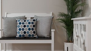 A white bench with three patterned cushions and a potted plant beside it. - Cozy 2 bedroom home in Orlando (Orlando)