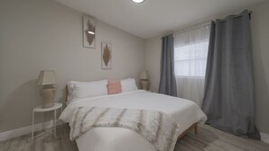 A bedroom with a bed, bedside tables, a lamp, and a window with curtains. - Cozy 2 bedroom home in Orlando (Orlando)