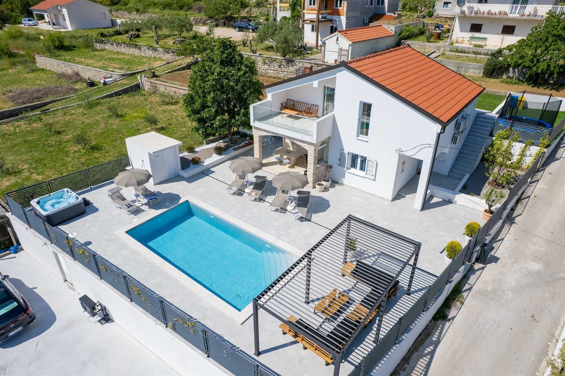 Une maison moderne à deux étages dotée d’une piscine, d’un espace salon extérieur et d’un patio couvert.