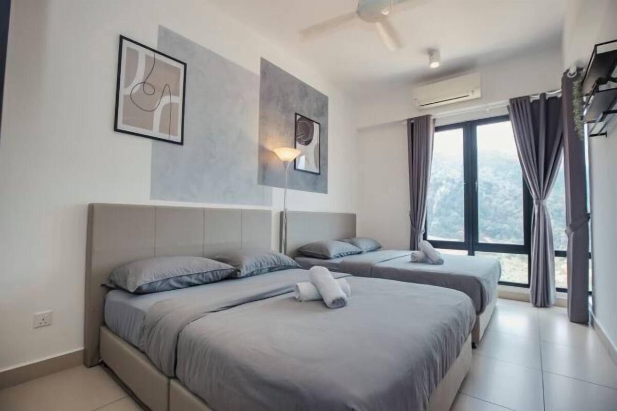 Une chambre d’hôtel moderne équipée de deux lits, d’un ventilateur de plafond, d’un appareil de climatisation et d’une grande fenêtre avec des rideaux.
