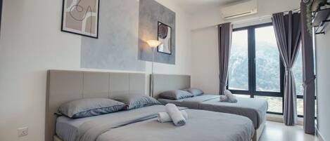 Une chambre d’hôtel moderne équipée de deux lits, d’un ventilateur de plafond, d’un appareil de climatisation et d’une grande fenêtre avec des rideaux.