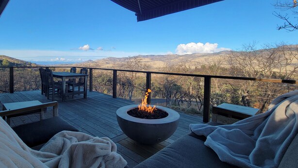 Una terraza con fogón, asientos exteriores y vistas al campo.