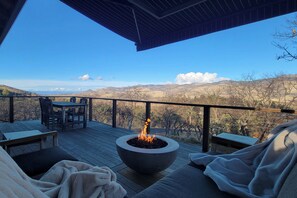 Um terraço com lareira, área de estar ao ar livre e vista para o campo.