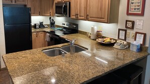 Eine Küche mit Granit Arbeitsplatten, Edelstahlgeräten, Holzschränken und einer Spüle mit zwei Becken.