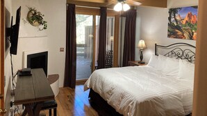Ein Schlafzimmer mit Bett, Deckenventilator, Fernseher, Kamin und einem Gemälde an der Wand.