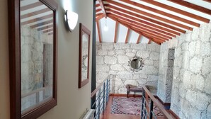 A wooden staircase with a stone wall and a view of the outside.
