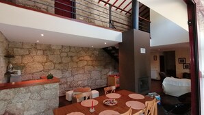A dining area with a stone wall, wooden table, and chairs.