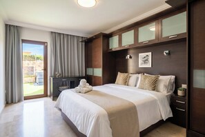 A hotel room with a large bed, a desk, and a view of the outdoors. - Oasis Tauro beach 3BR (Mogán)