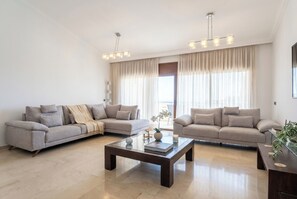 A modern living room with two sofas, a coffee table, and a large window with curtains.