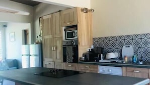 A modern kitchen with wooden cabinets, a central island, a microwave, and a sink. - Roucou room in the heart of nature, view of Mont Pelée (Le Morne Rouge)