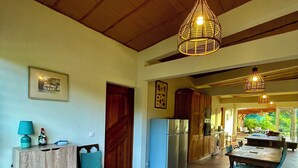 A spacious kitchen with a dining area, wooden ceiling, and tiled floor. - Roucou room in the heart of nature, view of Mont Pelée (Le Morne Rouge)