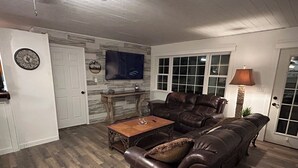 Ein Wohnzimmer mit einem braunen Ledersofa, einem Holztisch und einem Kamin aus Stein.