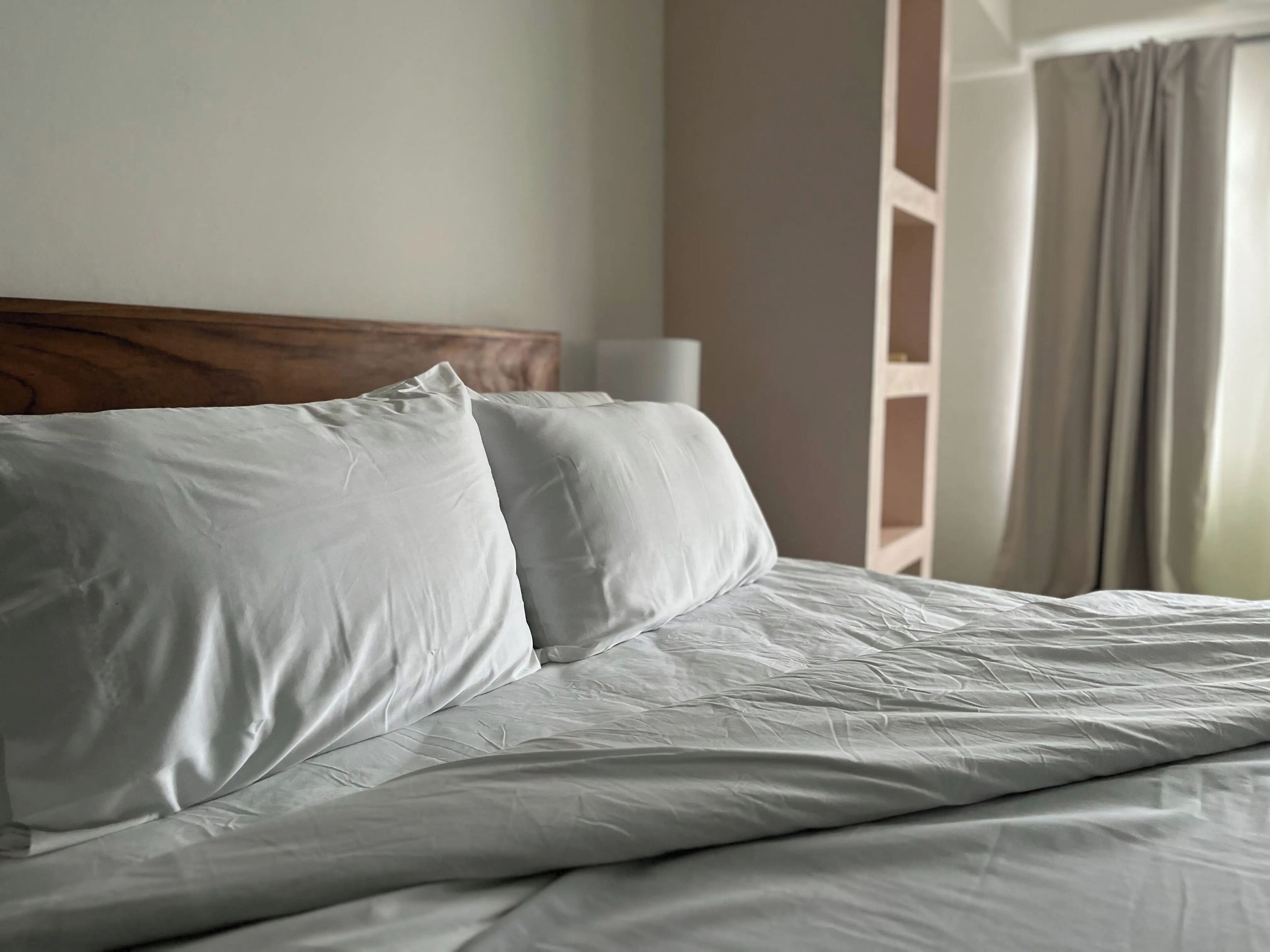 Un letto rifatto con lenzuola bianche in una camera d'albergo.