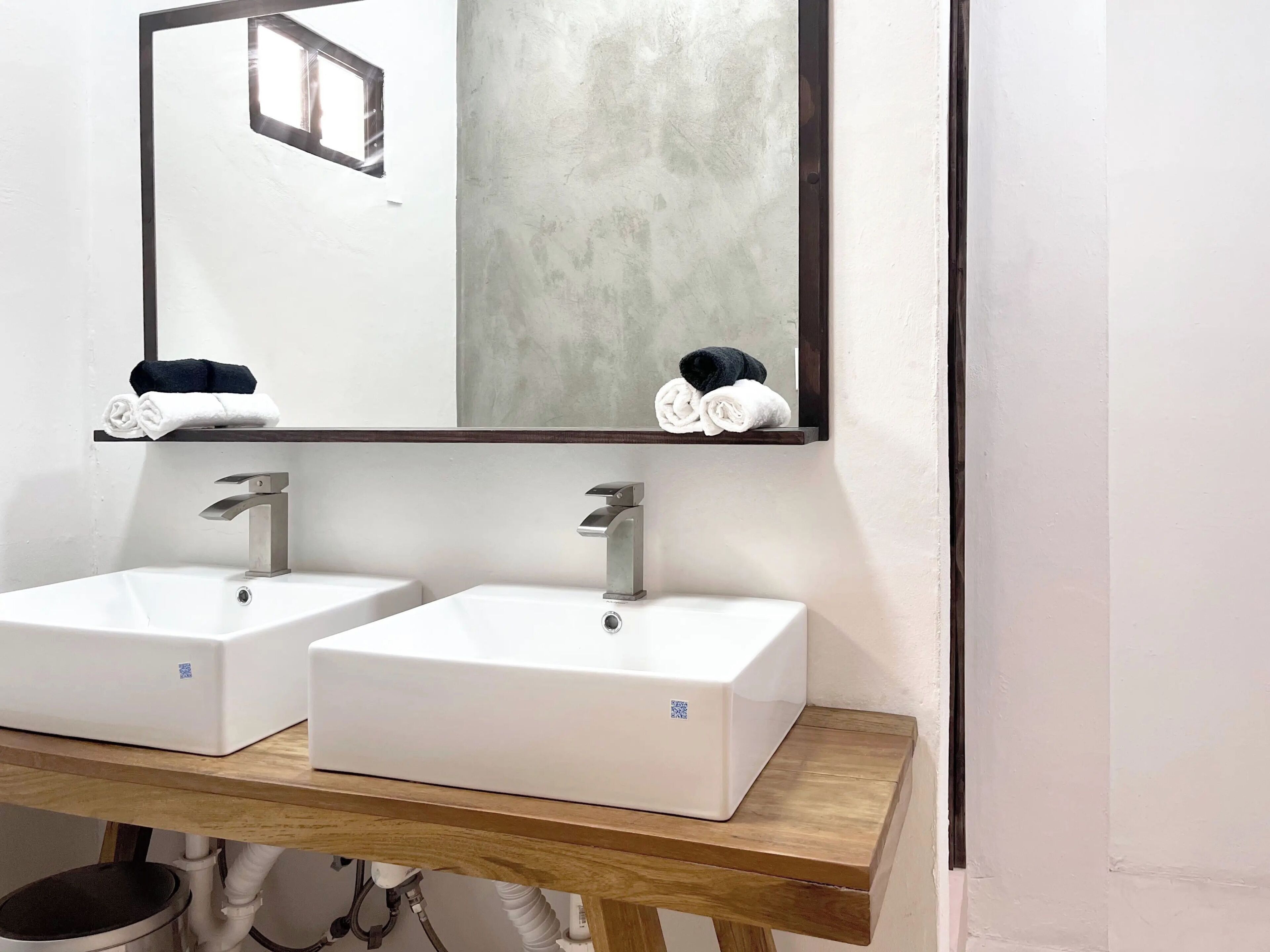 A bathroom with two white sinks, a mirror, and a wooden countertop.