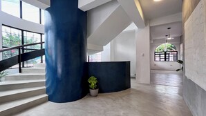 A modern interior with a staircase, a large blue pillar, and a potted plant. - Ipan Noya (Santa Tecla)
