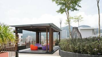 A rooftop terrace with seating, a pergola, and a view of the city.