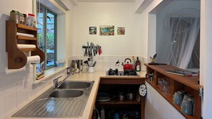 Une cuisine compacte équipée de deux éviers, d’une cuisinière à gaz et d’une fenêtre donnant sur un paysage agréable.