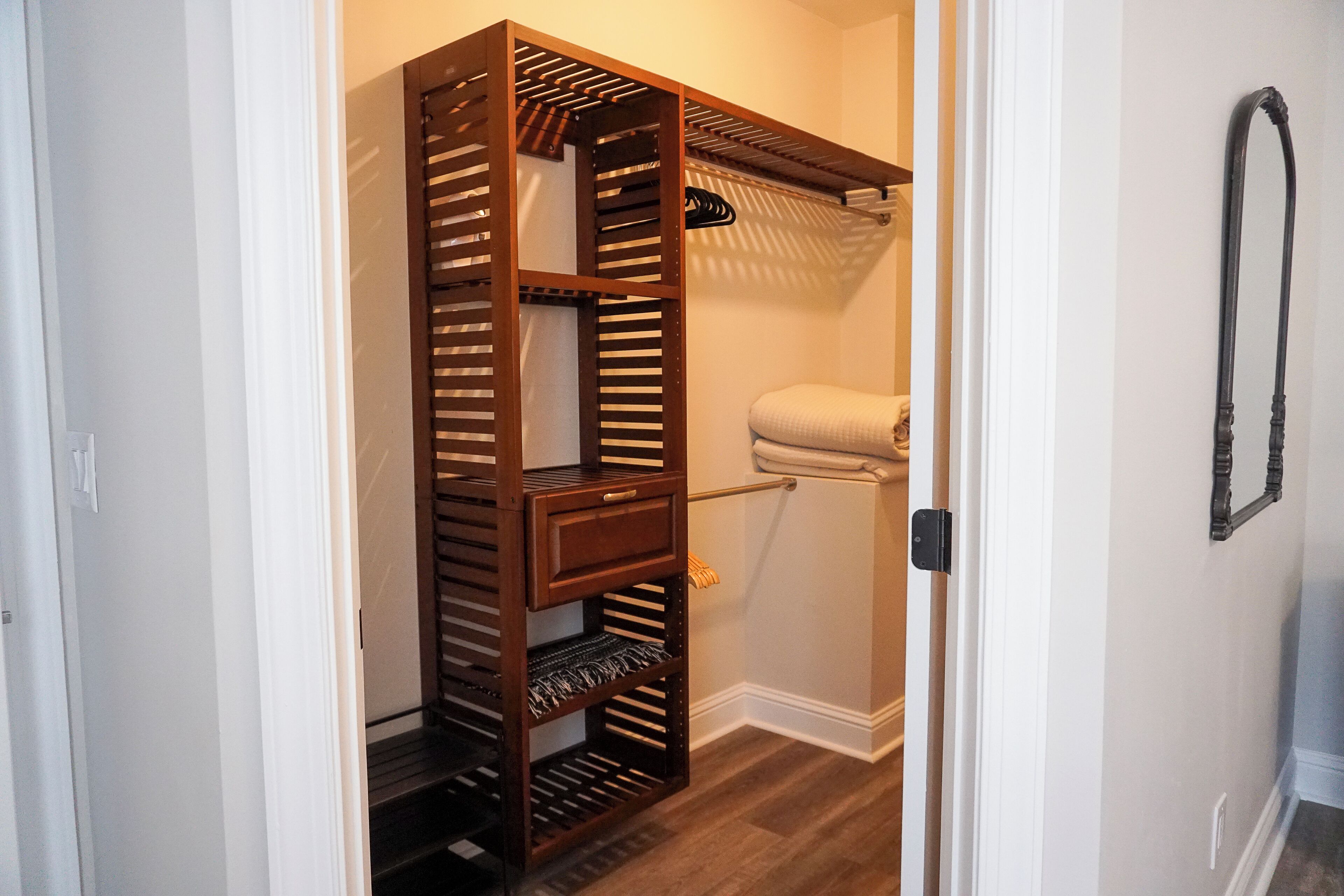 A walk-in closet with multiple shelves and hanging space, a toilet, and a towel rack.