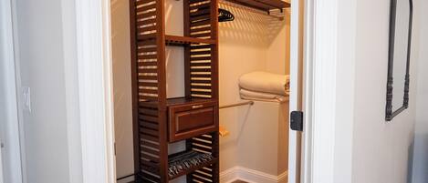 A walk-in closet with multiple shelves and hanging space, a toilet, and a towel rack.
