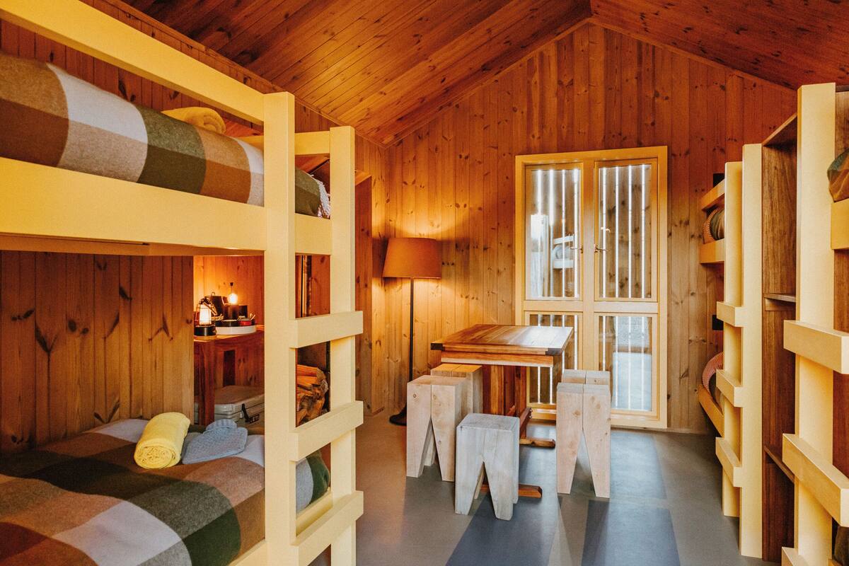 Une cabane en bois avec des lits superposés, une table et une fenêtre.
