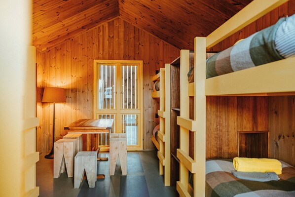 A wooden cabin room with bunk beds, a table, and a bench. - The Great Glenorchy Alpine Base Camp (Glenorchy)